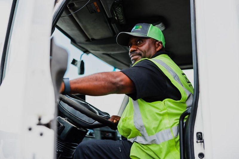 CWS employee opening collection truck door while looking out